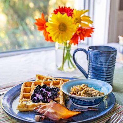 This image is of a plate of waffles and a bouquet of flowers that were grown on-site at our Cape Breton Bed and Breakfast.